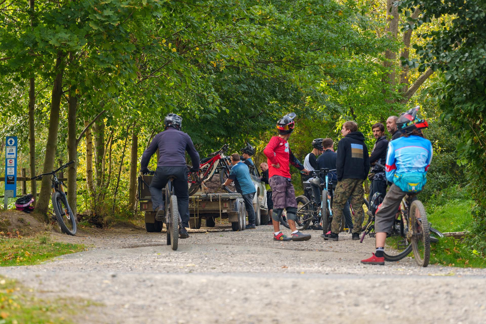 Grupa rowerzystów górskich przygotowuje się do startu na leśnej ścieżce w słoneczne, jesienne popołudnie.