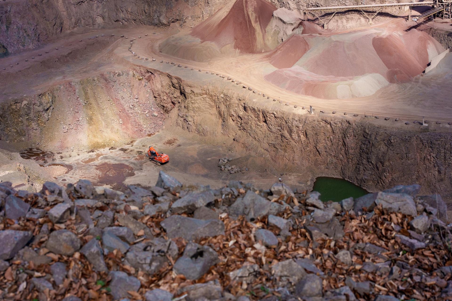 Widok na kopalnię odkrywkową z charakterystycznymi, kolorowymi warstwami ziemi i skalistym terenem na pierwszym planie.