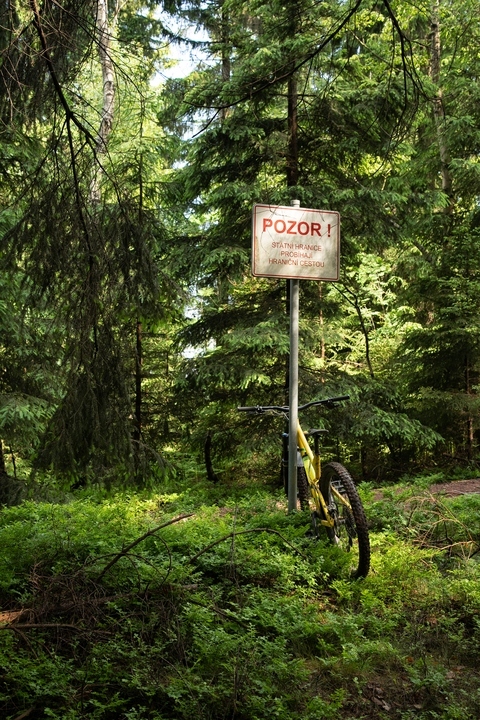 Zdjęcie roweru opartego o znak (w języku czeskim) o przebiegu granicy